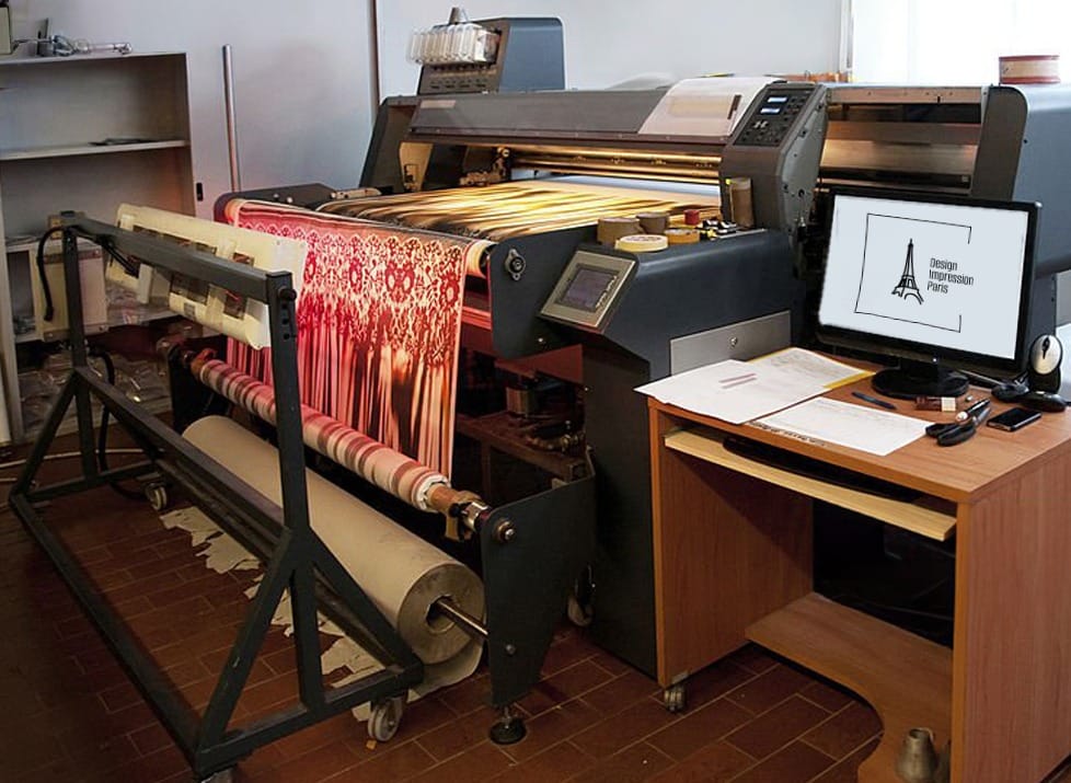 Impression sur tissu dans un atelier avec une machine professionnelle, déroulant un tissu imprimé avec des motifs colorés.
